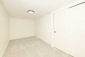 Unfurnished bedroom with light carpet and baseboards