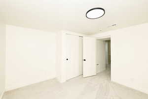 Unfurnished bedroom featuring light carpet and a closet