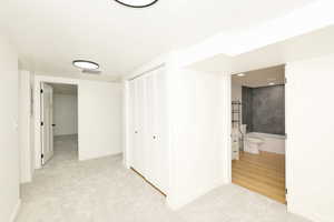 Hallway featuring light carpet and baseboards