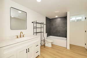 Bathroom featuring vanity, light wood finished floors, bathtub / shower combination, a textured ceiling, and recessed lighting