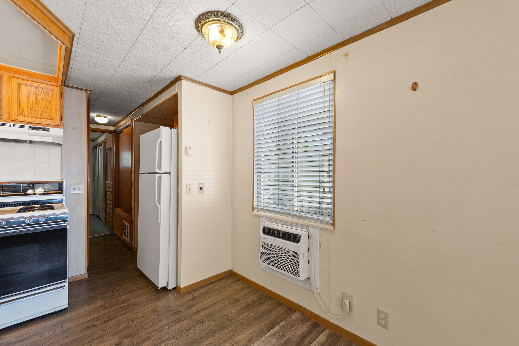 Kitchen with gas stove, freestanding refrigerator, crown molding, dark wood finished floors, and wood finish cabinets