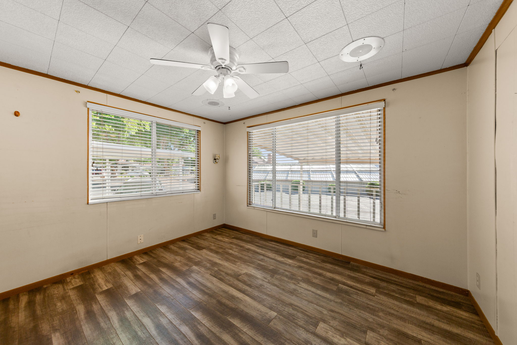 Empty room with ceiling fan, dark wood-style floors, and ornamental molding