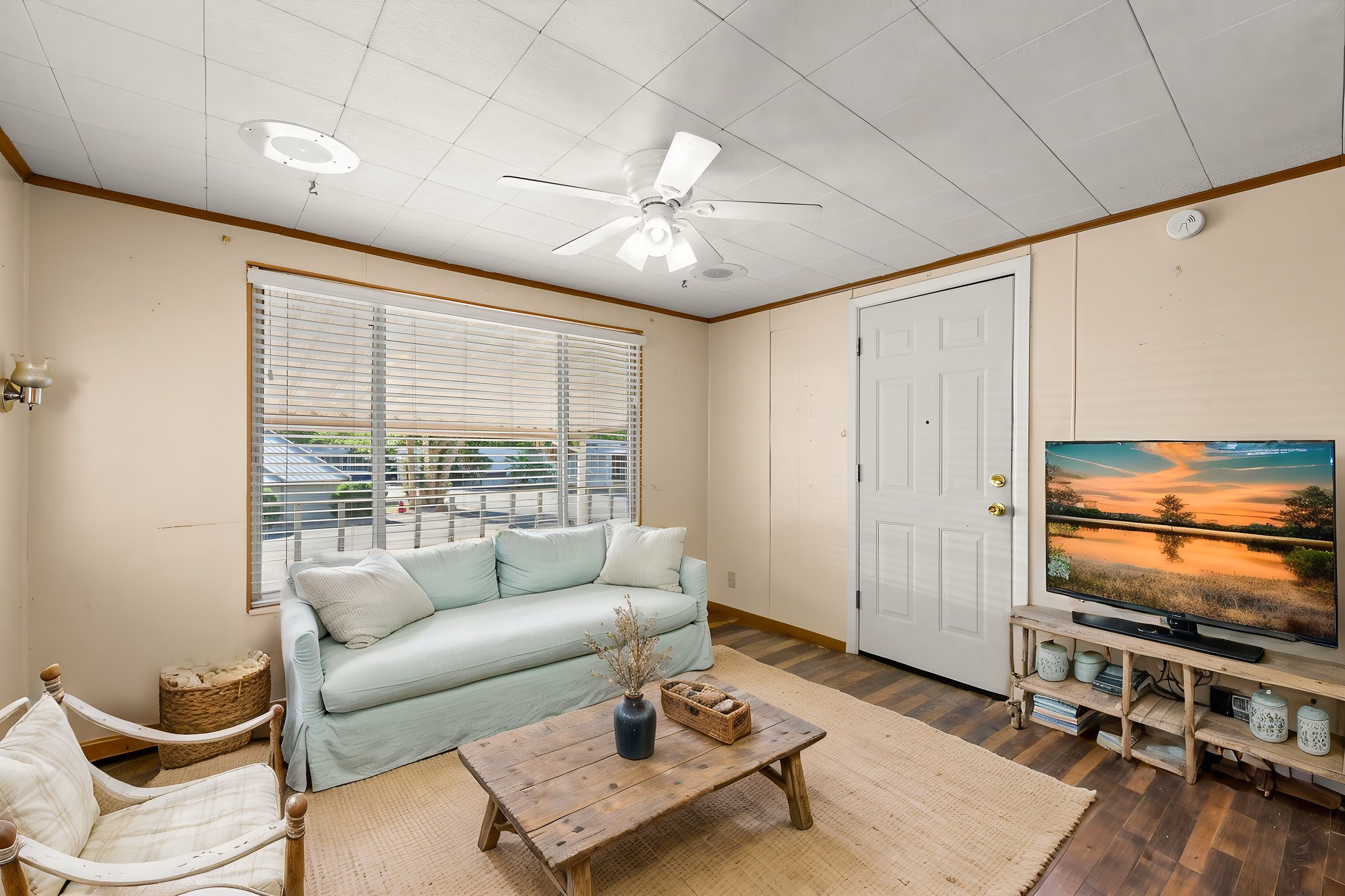 Living area with ceiling fan, dark wood finished floors, and crown molding