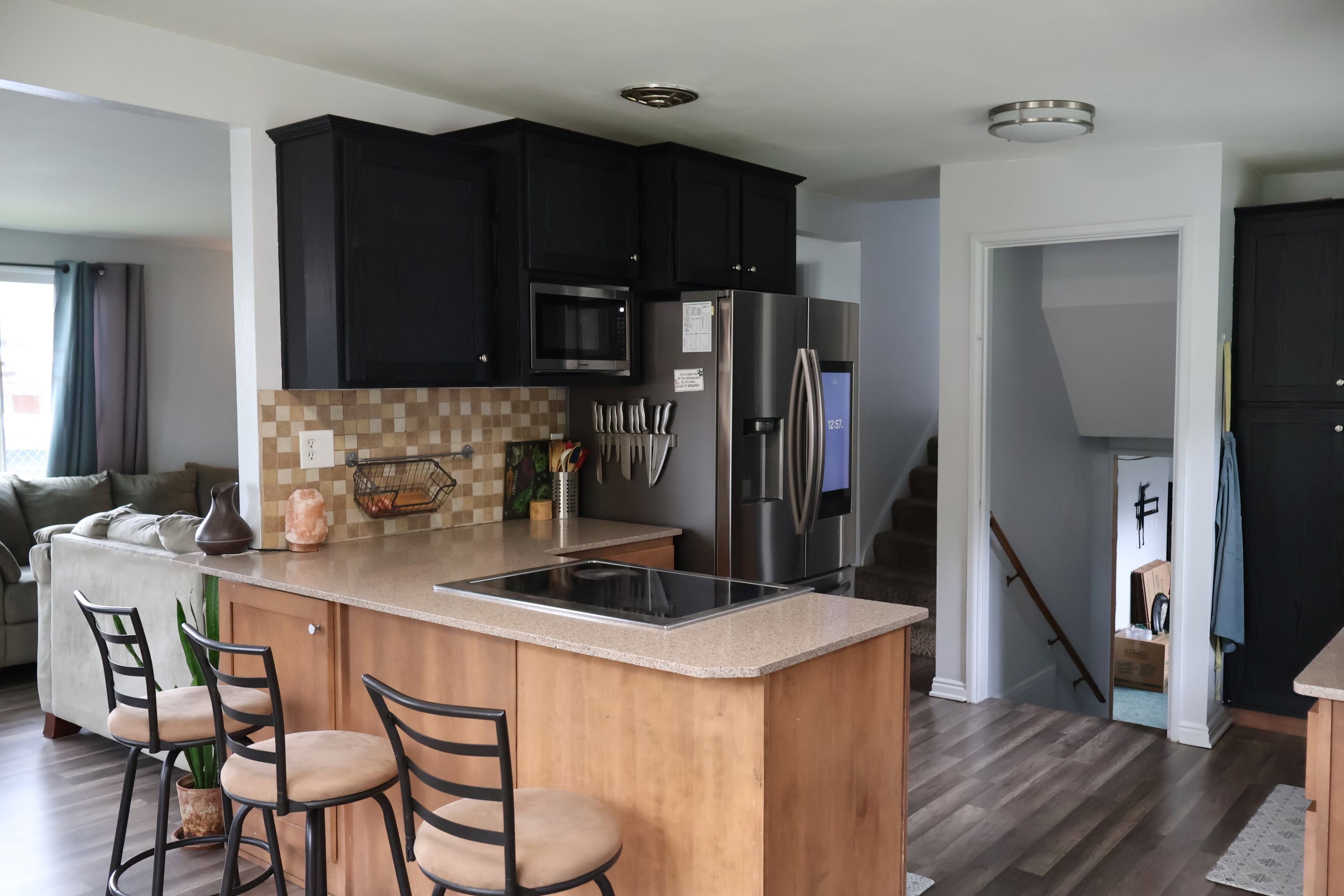 Kitchen with a peninsula, dark cabinets, dark wood-style flooring, and decorative backsplash