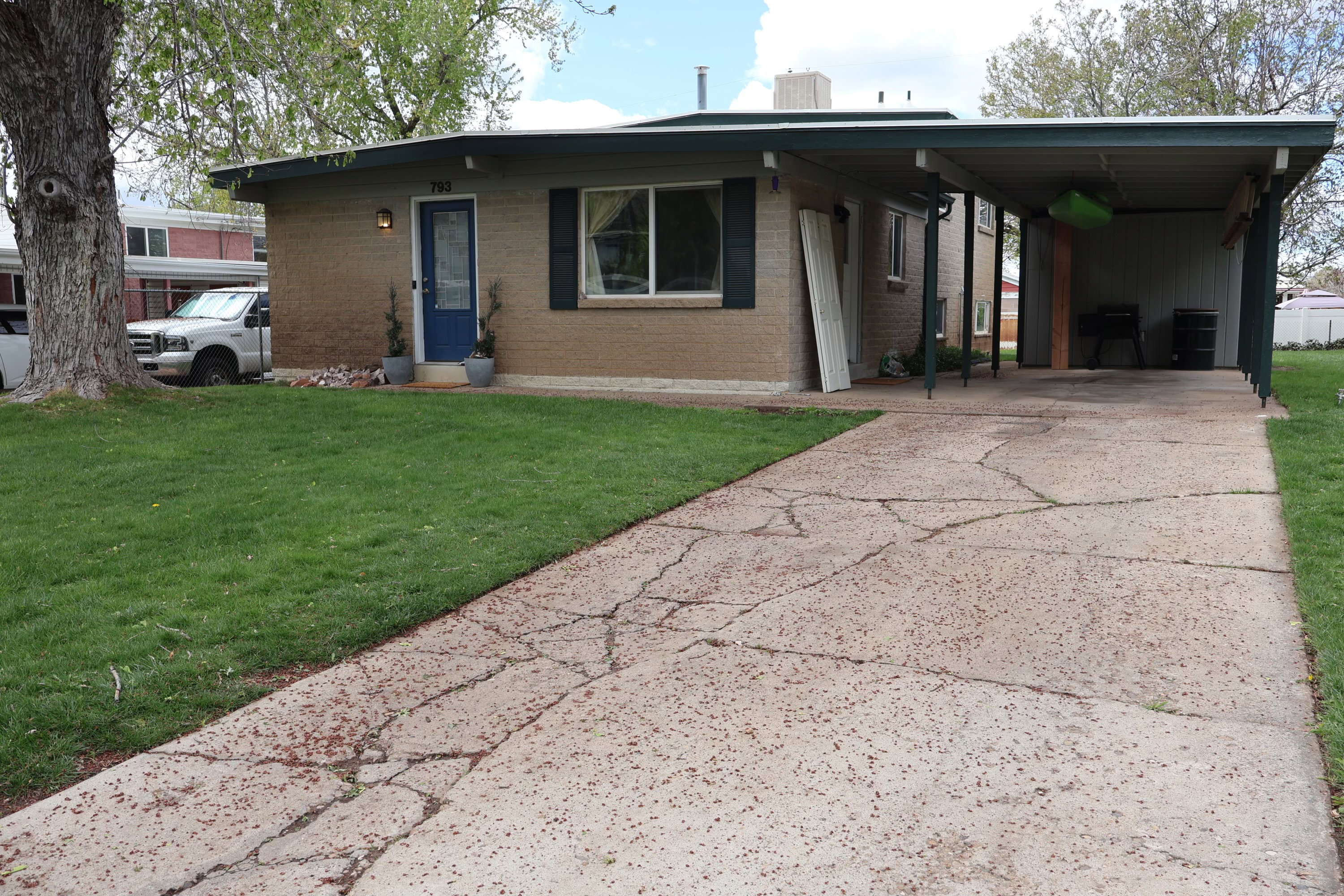 View of front facade with a front yard, concrete driveway, an attached carport, and brick siding