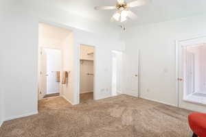 Unfurnished bedroom with a spacious closet, carpet flooring, and ceiling fan