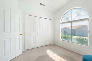 Unfurnished bedroom with light colored carpet, vaulted ceiling, and a closet