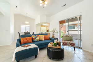 Living area featuring lofted ceiling, light tile patterned flooring, and a ceiling fan