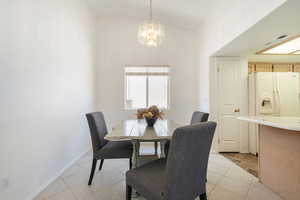 Dining space with hanging lights, lofted ceiling, and light tile patterned floors