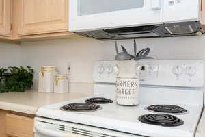 Kitchen with white appliances, light countertops, and light wood finish cabinetry