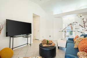 Living area with lofted ceiling and light tile patterned flooring
