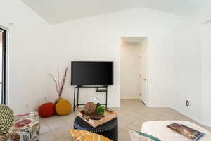 Living area with light tile patterned floors and lofted ceiling