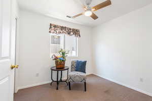 Living area featuring dark carpet and ceiling fan