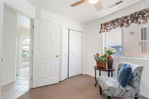 Living area featuring light colored carpet and ceiling fan