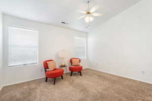Living area with lofted ceiling, a ceiling fan, and carpet