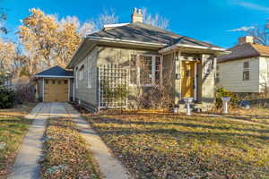 Bungalow-style house featuring a chimney, a front lawn, and driveway