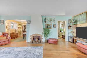 Living room featuring light wood-type flooring, hanging lights, arched walkways, and a fireplace with flush hearth