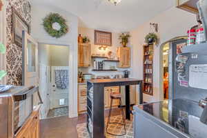 Kitchen featuring light wood finish cabinets, range with electric stovetop, arched walkways, open shelves, and freestanding refrigerator