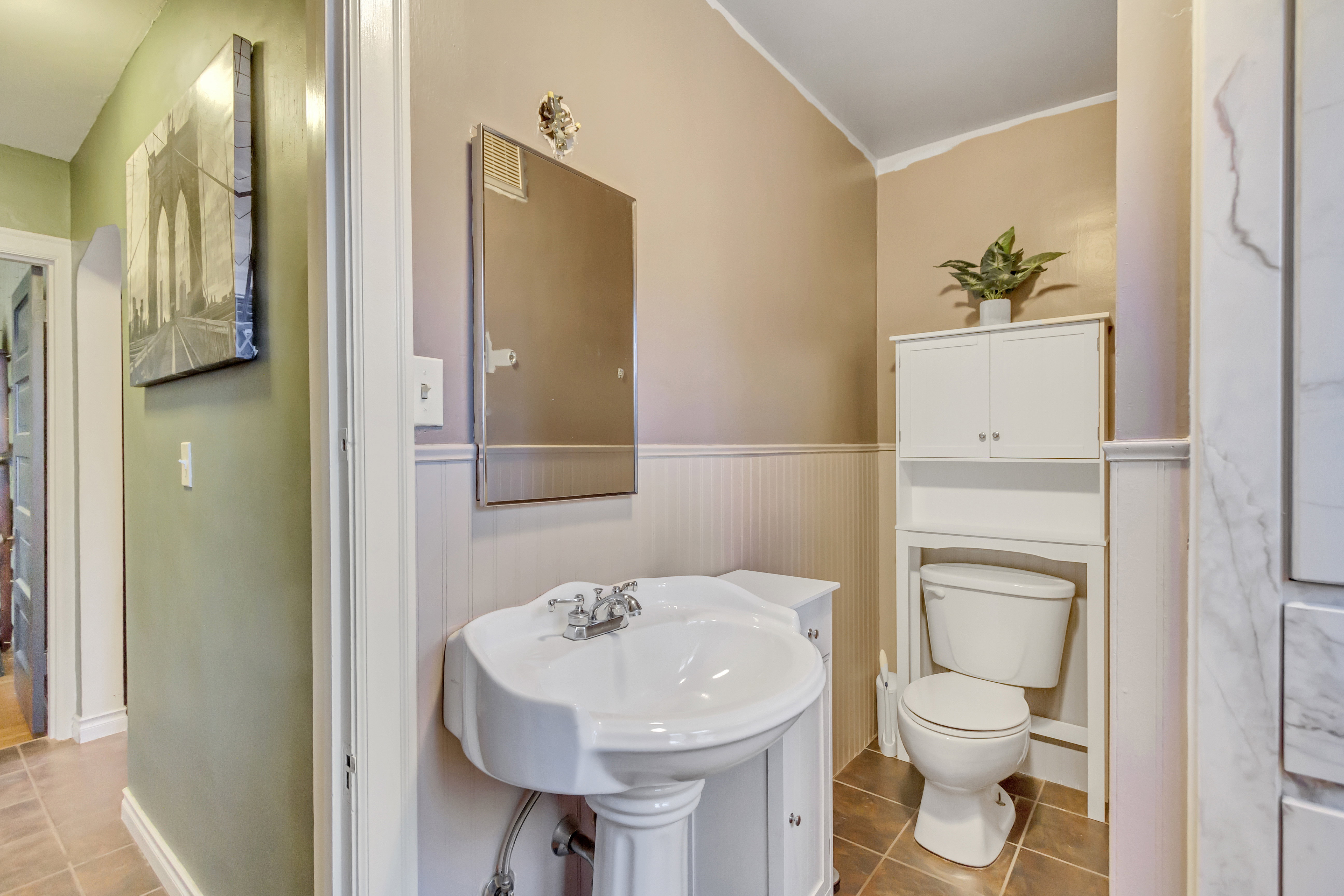 Half bathroom featuring a wainscoted wall, ornamental molding, and light tile patterned flooring