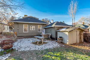 Back of property featuring a storage unit, a chimney, and a shingled roof