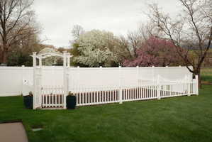 Expansive lawn area featuring a white vinyl privacy fence and a charming white picket fence enclosure