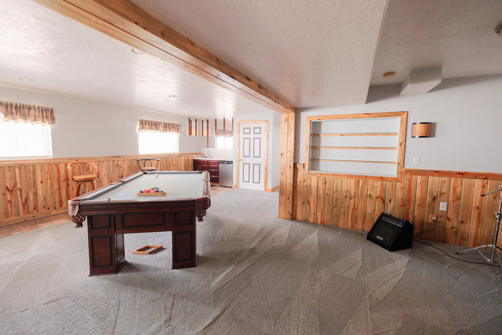 Spacious lower-level room featuring wood-paneled wainscoting and light carpeting