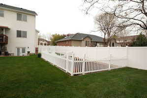 Expansive green lawn featuring a full white privacy fence enclosing the property