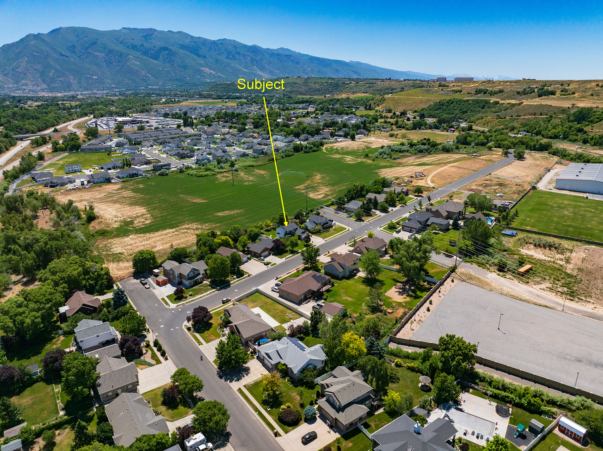 Aerial perspective of a residential neighborhood with surrounding green spaces and distant mountains
