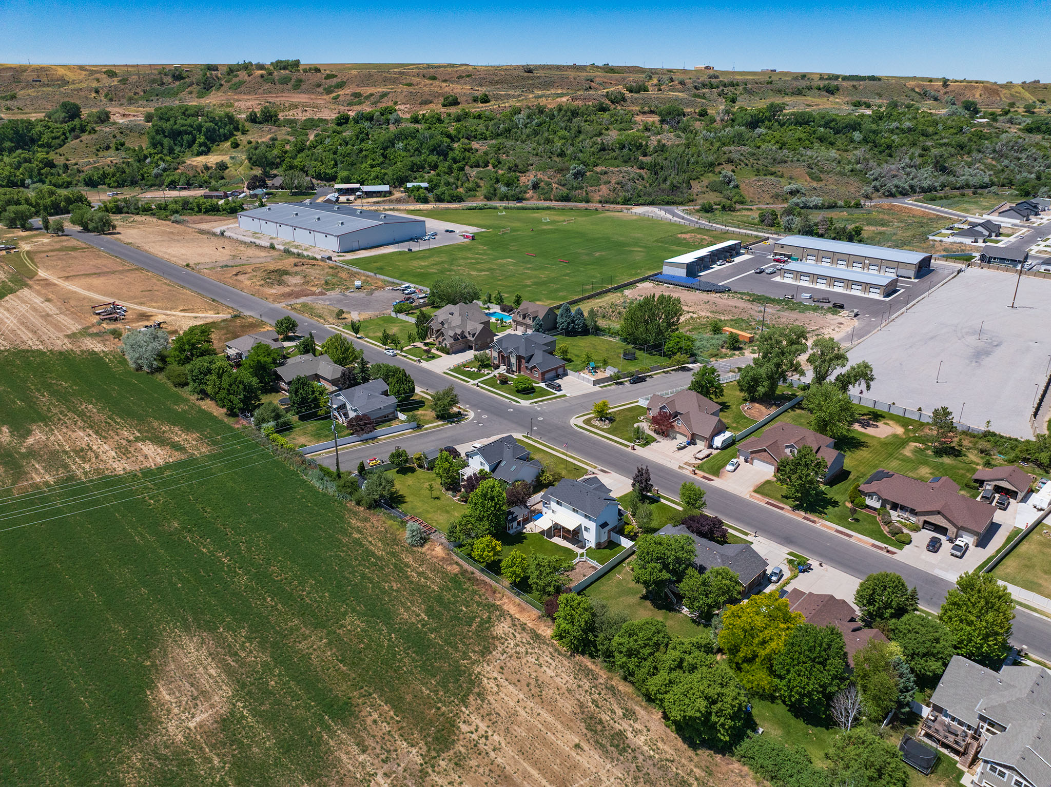 Aerial perspective showcasing a residential area bordered by cultivated fields and natural hillsides