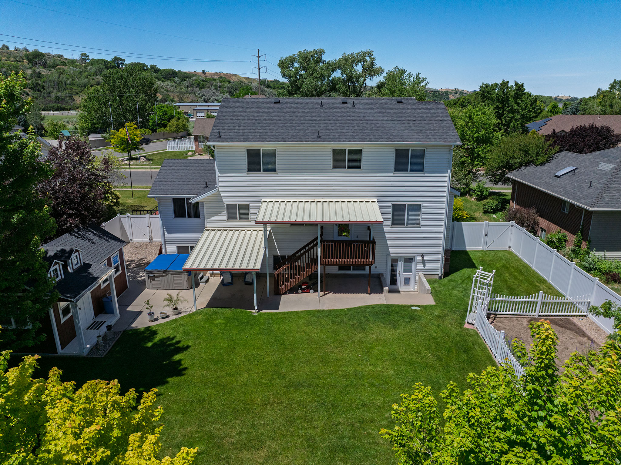 Spacious rear exterior featuring a two-story residence with white siding, a covered upper deck, and a lower-level covered patio