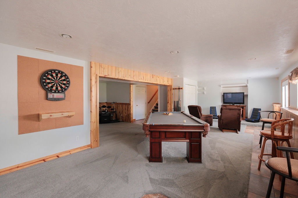 Spacious recreation room featuring a billiards table, gray carpeting, and a dedicated dartboard area with cork backing