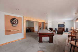 Spacious recreation room featuring a billiards table, gray carpeting, and a dedicated dartboard area with cork backing