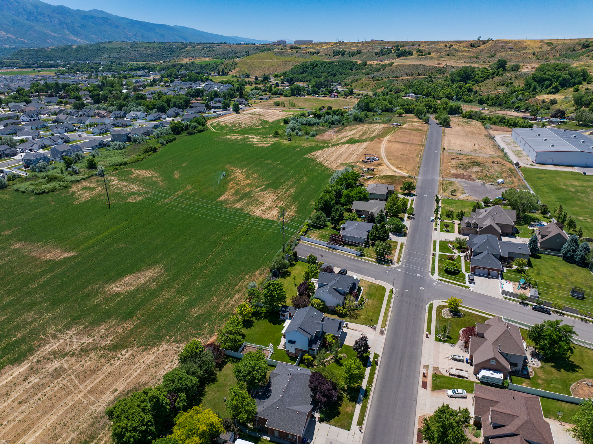 Expansive aerial showcasing a residential neighborhood with established homes, paved streets, and green spaces