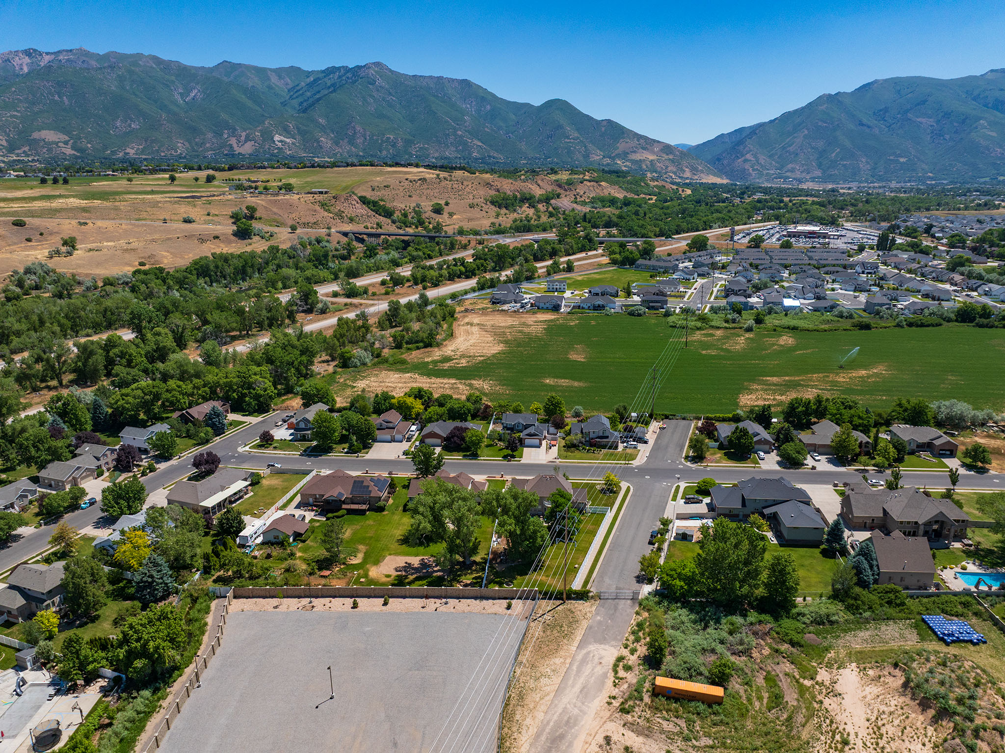 Expansive aerial perspective showcasing a residential neighborhood with surrounding green spaces and distant mountain range