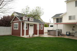 Manicured lawn with a detached storage shed, featuring dormer windows and a white entry door