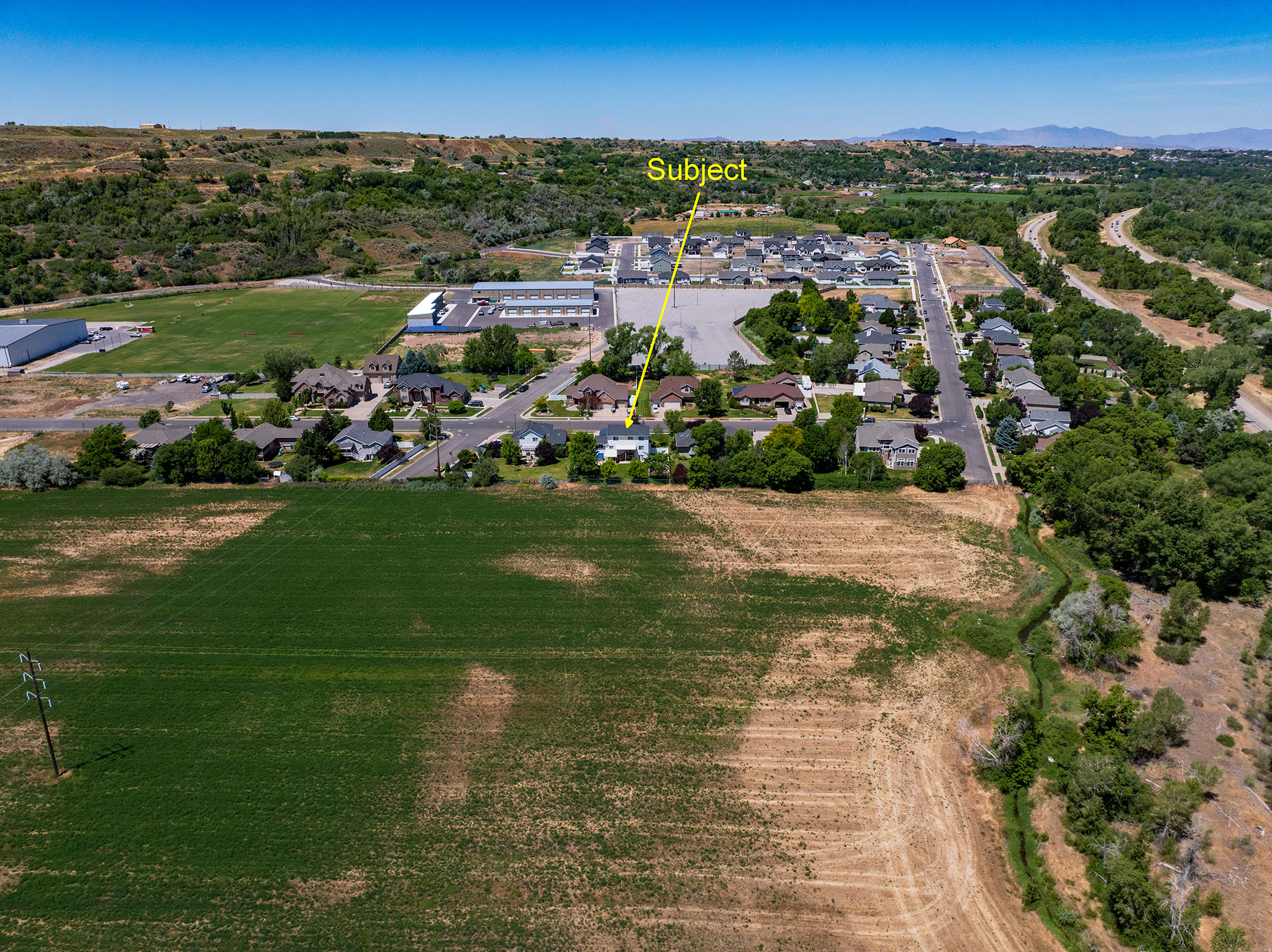 Aerial perspective of the property, featuring a surrounding residential area and undeveloped land