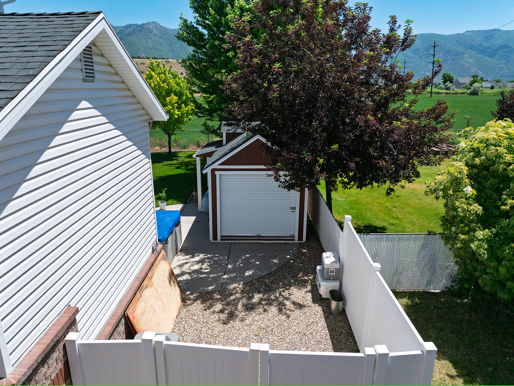 Detached garage with white roll-up door, positioned on a concrete pad