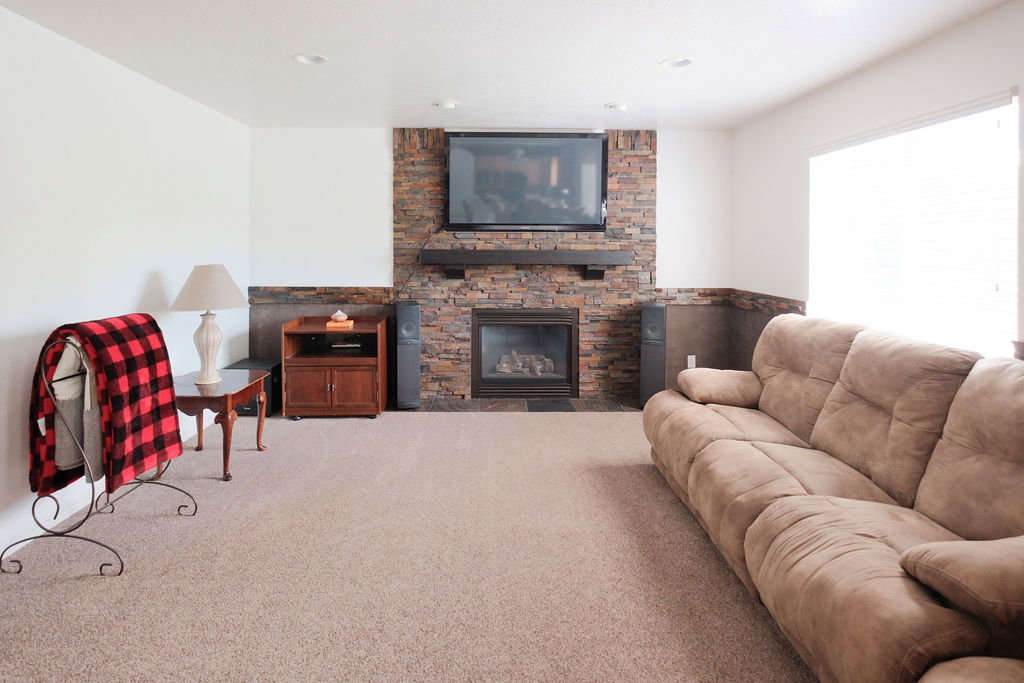 Living area featuring a floor-to-ceiling stacked stone fireplace with a dark wood mantel and a built-in gas insert