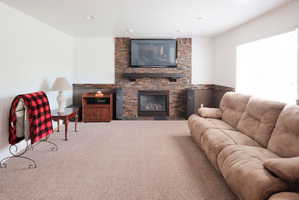 Living area featuring a floor-to-ceiling stacked stone fireplace with a dark wood mantel and a built-in gas insert