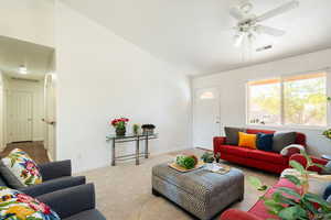 Living room featuring carpet flooring, ceiling fan, and lofted ceiling
