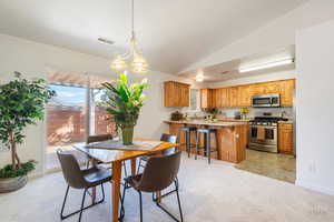 Dining area with light colored carpet, a chandelier, and lofted ceiling