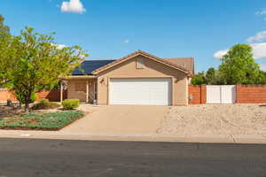 View of front of home with a tiled roof, a garage, a gate, driveway, and solar panels