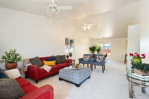 Living room featuring carpet floors, lofted ceiling, a ceiling fan, and hanging lights