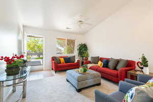 Carpeted living area featuring ceiling fan and vaulted ceiling