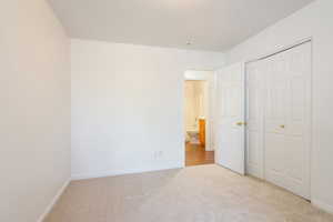 Unfurnished bedroom featuring light carpet and a closet