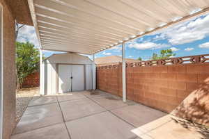 Fenced backyard with a storage unit and a patio area