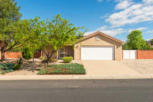 View of front of property featuring an attached garage, concrete driveway, and stucco siding
