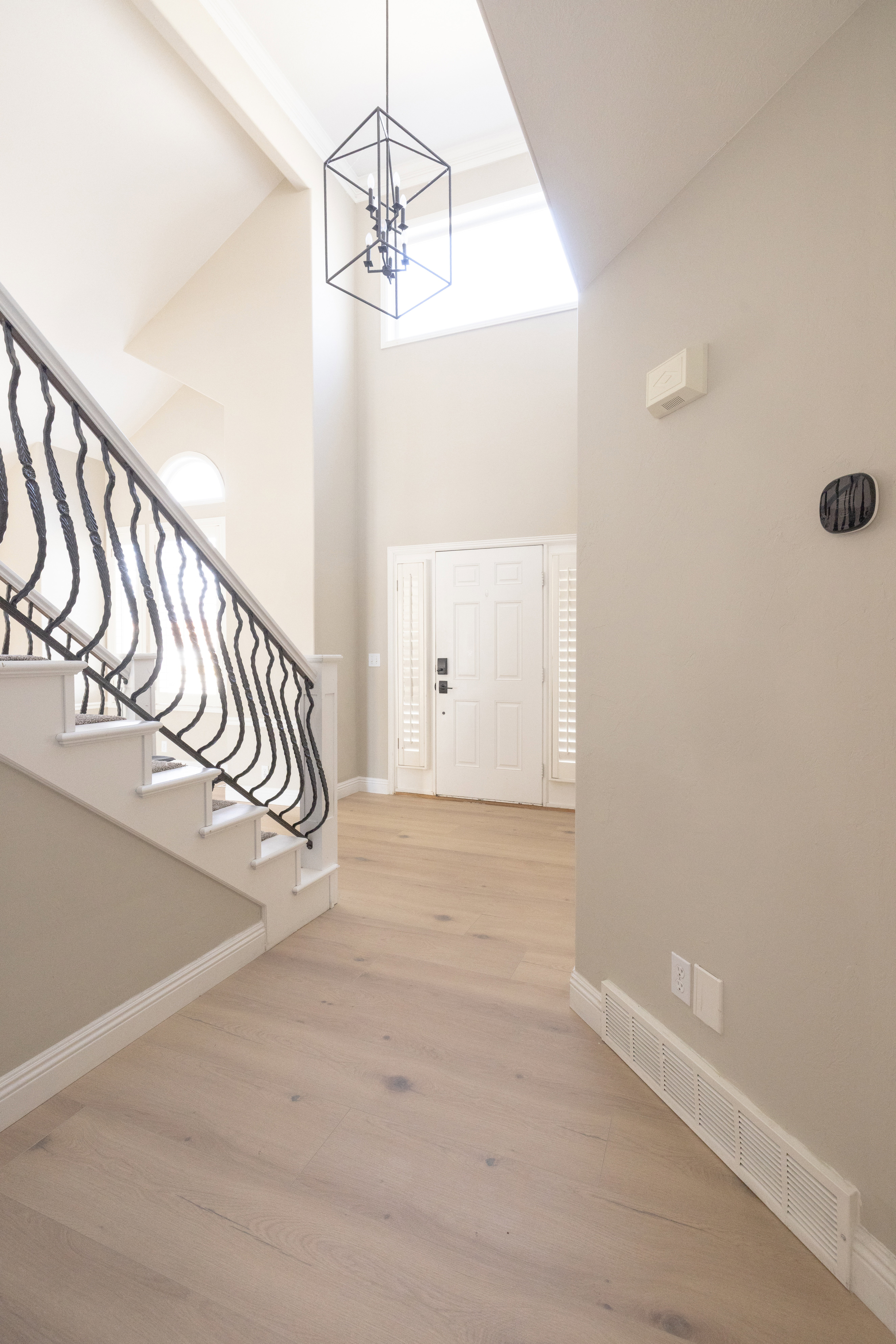 Foyer entrance featuring light wood-style floors, suspended lighting, and lofted ceiling