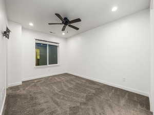 Spare room featuring dark colored carpet, ceiling fan, and recessed lighting
