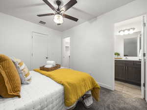 Bedroom featuring light carpet, a walk in closet, a ceiling fan, and connected bathroom